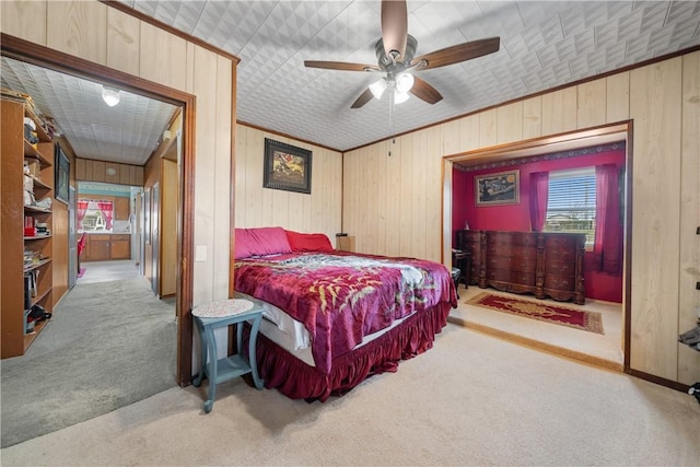 bedroom with light carpet, ornamental molding, ceiling fan, and wooden walls