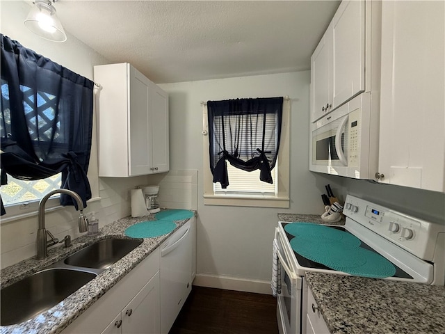 kitchen with sink, light stone counters, dark hardwood / wood-style flooring, white appliances, and white cabinets