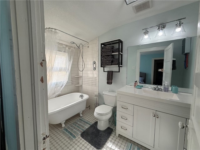 bathroom featuring tile patterned floors, a bathing tub, a textured ceiling, toilet, and lofted ceiling