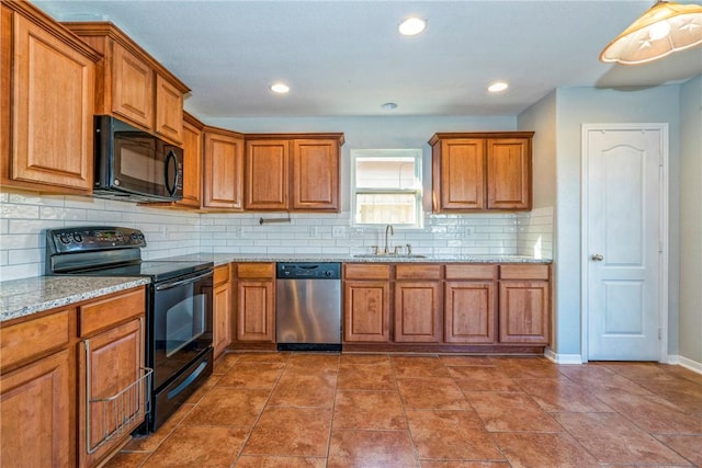 kitchen with light stone counters, sink, tasteful backsplash, and black appliances