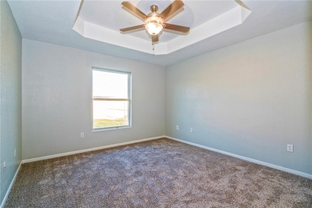 carpeted empty room featuring a tray ceiling and ceiling fan