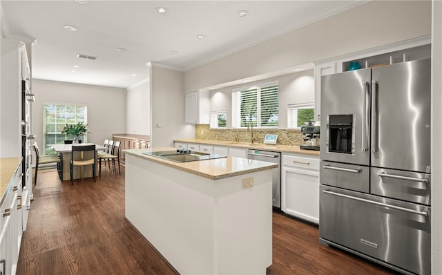 kitchen featuring stainless steel appliances, a center island, white cabinets, and light stone counters