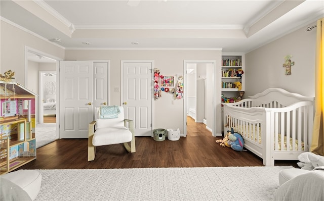 bedroom featuring dark hardwood / wood-style flooring, crown molding, and a raised ceiling