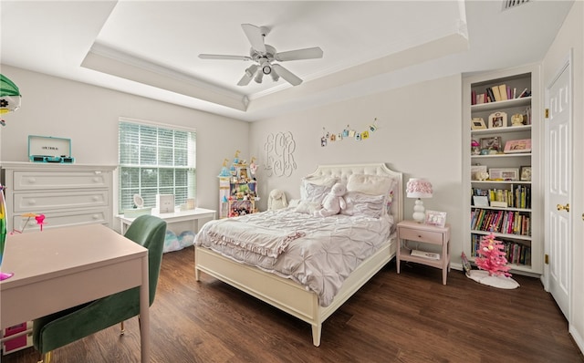 bedroom with ornamental molding, ceiling fan, dark hardwood / wood-style flooring, and a tray ceiling