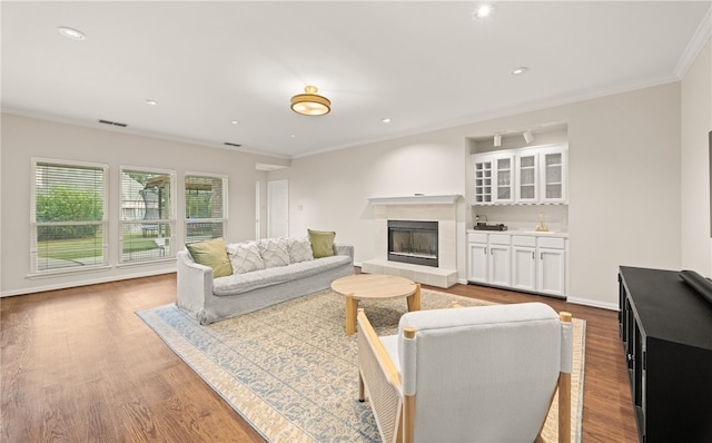 living room with a tiled fireplace, hardwood / wood-style floors, and ornamental molding