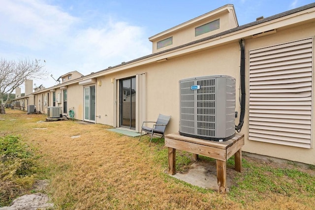 back of house with cooling unit and a lawn