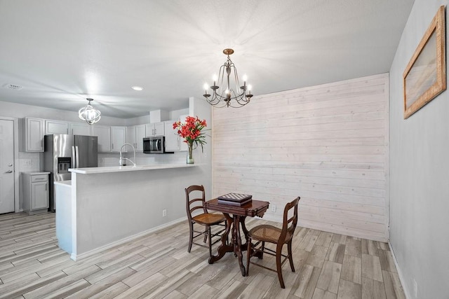 dining space with wooden walls, a chandelier, and sink