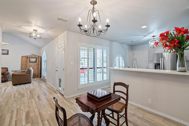 dining room featuring lofted ceiling, sink, and an inviting chandelier