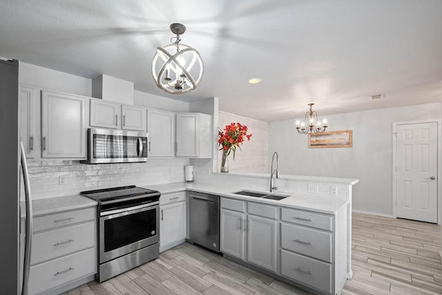 kitchen featuring stainless steel appliances, sink, pendant lighting, and a chandelier