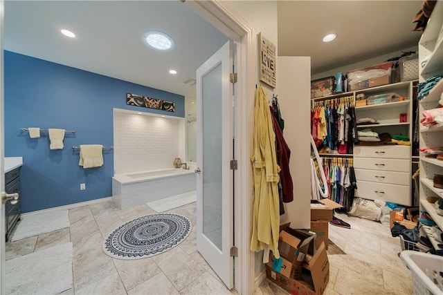 bathroom with a garden tub, recessed lighting, and a walk in closet
