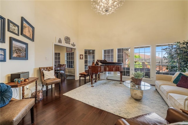 living area featuring a high ceiling, a chandelier, and dark wood-type flooring