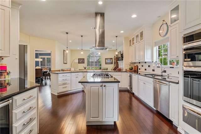 kitchen featuring a peninsula, dark countertops, a sink, a warming drawer, and stainless steel appliances