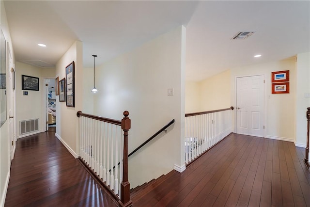 hall with baseboards, an upstairs landing, dark wood-style flooring, and visible vents