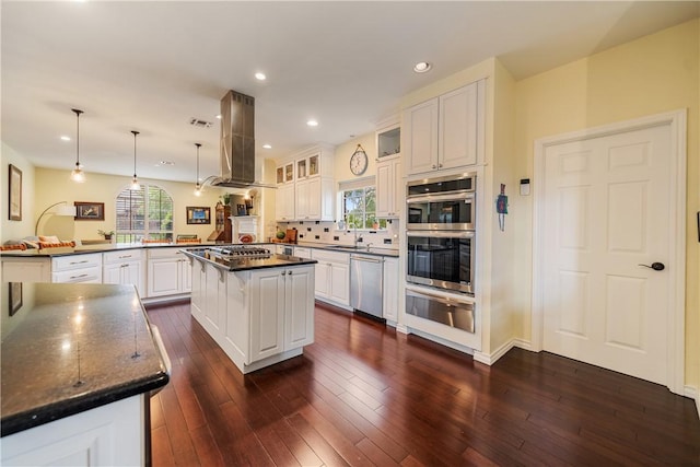 kitchen featuring ventilation hood, appliances with stainless steel finishes, a warming drawer, and a healthy amount of sunlight