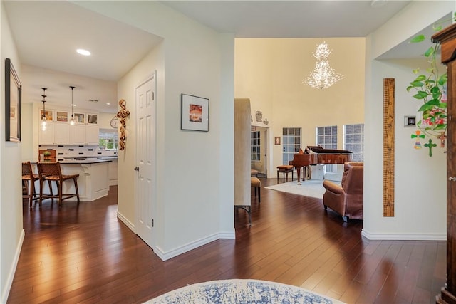 hall featuring dark wood-style flooring, baseboards, an inviting chandelier, and recessed lighting
