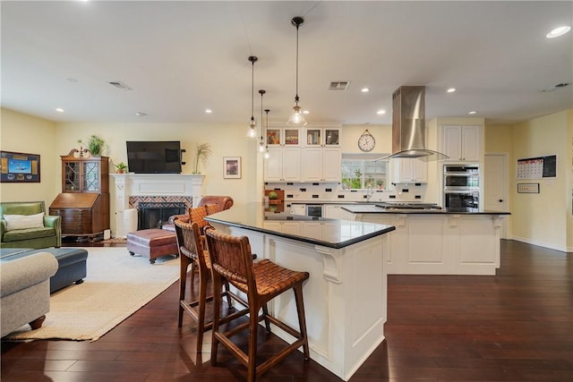 kitchen featuring visible vents, a kitchen island, dark countertops, island exhaust hood, and stainless steel appliances