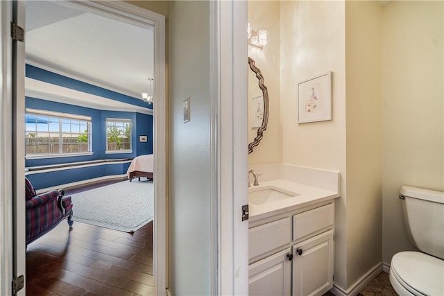 ensuite bathroom featuring vanity, baseboards, toilet, and wood finished floors