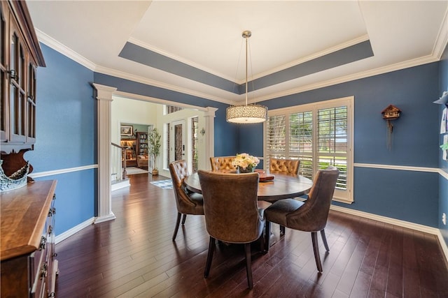 dining room with dark wood-type flooring, ornamental molding, a raised ceiling, and baseboards