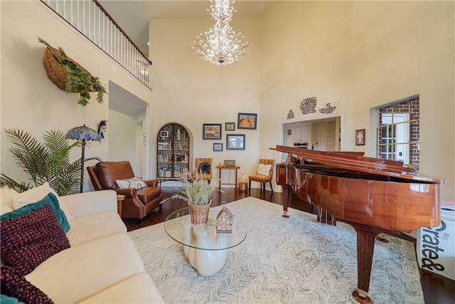 sitting room with a notable chandelier, wood finished floors, and a towering ceiling