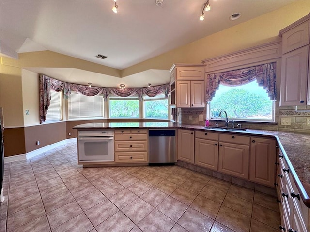 kitchen with stainless steel dishwasher, a sink, visible vents, oven, and a peninsula