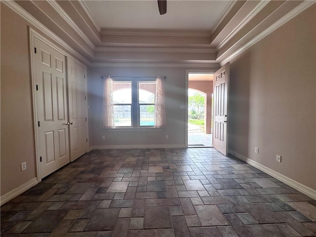 foyer with crown molding, stone tile floors, baseboards, and a tray ceiling