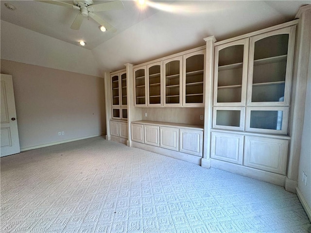empty room featuring baseboards, light carpet, a ceiling fan, and vaulted ceiling
