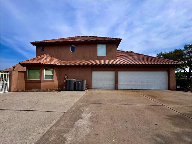 view of side of home with concrete driveway, central air condition unit, an attached garage, and stucco siding