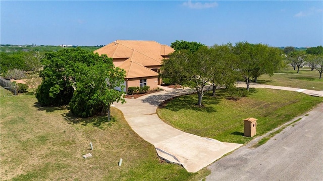 view of front of property with a tile roof, a front yard, stucco siding, and curved driveway