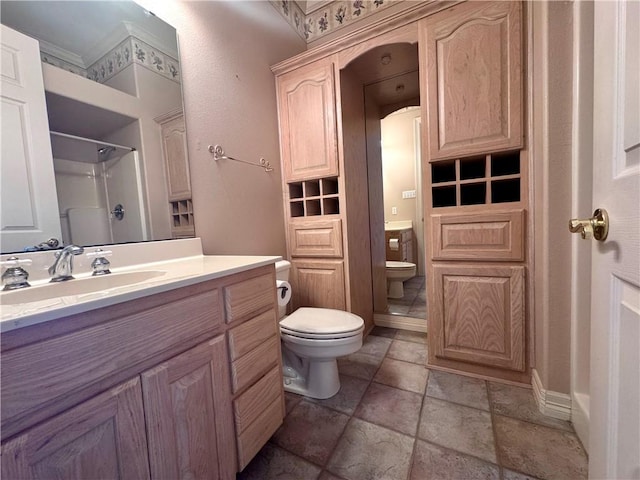 full bathroom with stone tile flooring, toilet, vanity, baseboards, and a shower