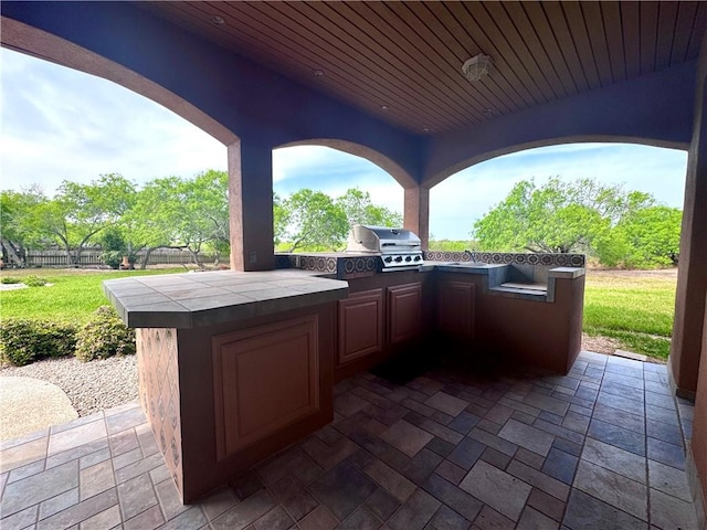view of patio / terrace featuring an outdoor kitchen, fence, grilling area, and outdoor wet bar