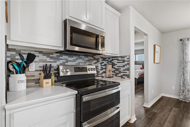 702 W 1st St, Bishop, TX 78343 - kitchen with dark wood-type flooring, white cabinetry, light countertops, stainless steel appliances, and baseboards