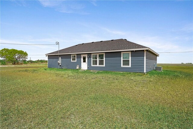 702 W 1st St, Bishop, TX 78343 - rear view of property featuring a shingled roof, cooling unit, and a lawn