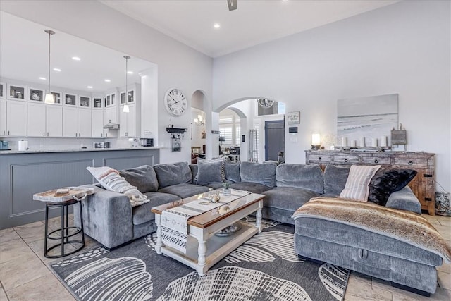 living area featuring recessed lighting, arched walkways, and a high ceiling