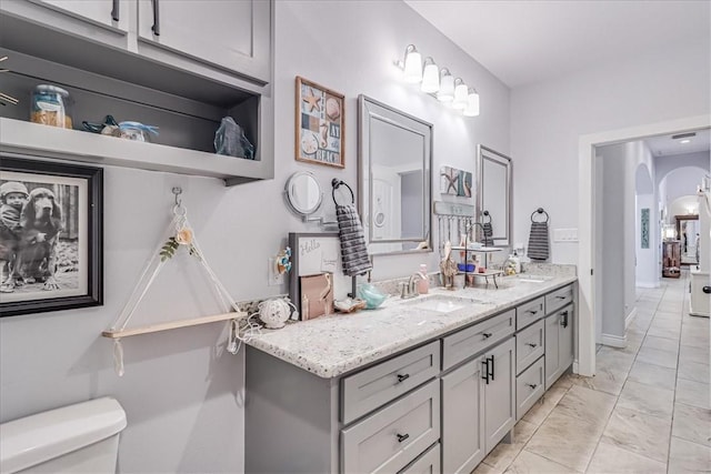 bathroom with marble finish floor, toilet, vanity, and baseboards