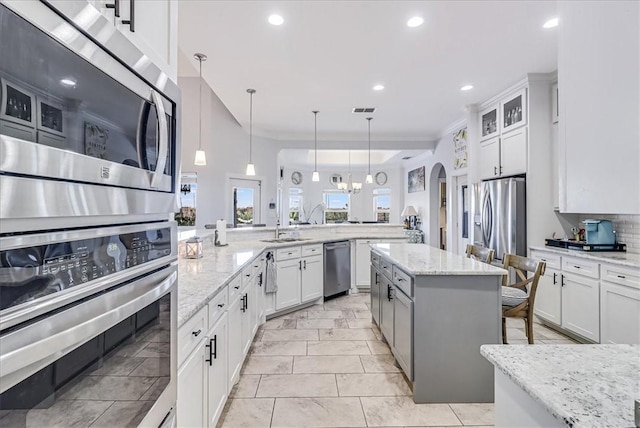 kitchen featuring arched walkways, a kitchen island, white cabinetry, and stainless steel appliances