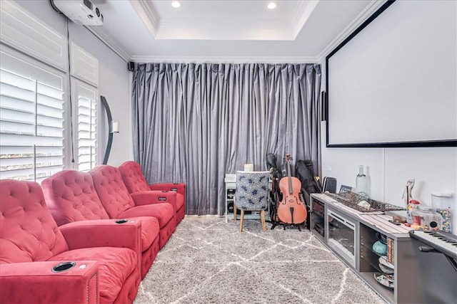 carpeted home theater room with a tray ceiling, recessed lighting, and ornamental molding