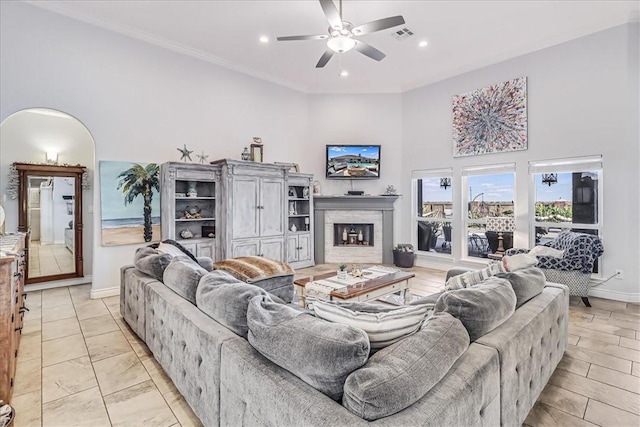 living area featuring ceiling fan, baseboards, recessed lighting, a fireplace, and arched walkways