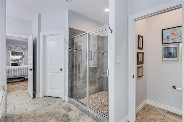 ensuite bathroom featuring a shower stall, ensuite bath, and baseboards