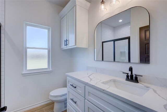 bathroom featuring toilet, vanity, a shower with shower door, and hardwood / wood-style flooring