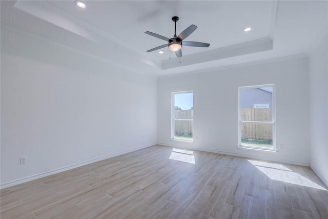 empty room featuring a tray ceiling, ceiling fan, light hardwood / wood-style flooring, and crown molding