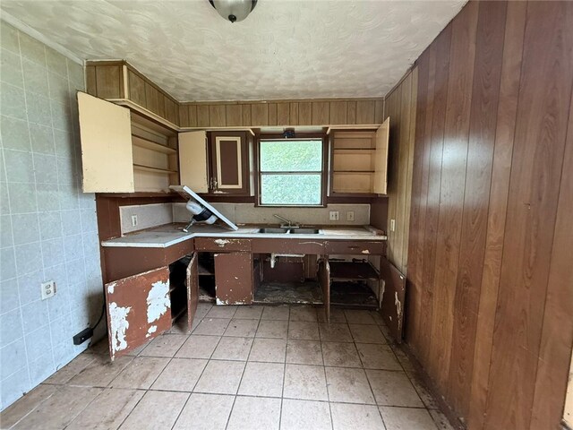 415 S Buchanan St, Beeville, TX 78102 - kitchen featuring light countertops, tile walls, light tile patterned flooring, a textured ceiling, and wooden walls