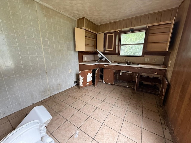 415 S Buchanan St, Beeville, TX 78102 - kitchen featuring light countertops, light tile patterned floors, ornamental molding, wood walls, and tile walls