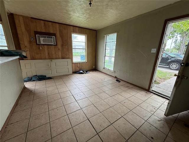 415 S Buchanan St, Beeville, TX 78102 - unfurnished dining area with a wall mounted AC, wood walls, a textured ceiling, and light tile patterned flooring