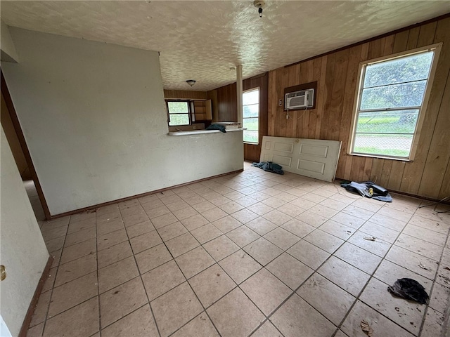 415 S Buchanan St, Beeville, TX 78102 - unfurnished living room featuring a wall mounted air conditioner, a textured ceiling, wooden walls, and light tile patterned floors
