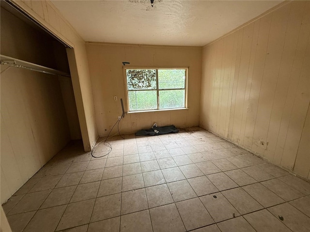 415 S Buchanan St, Beeville, TX 78102 - unfurnished bedroom featuring a closet, wood walls, and light tile patterned flooring