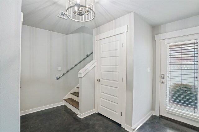 staircase with concrete flooring and a notable chandelier