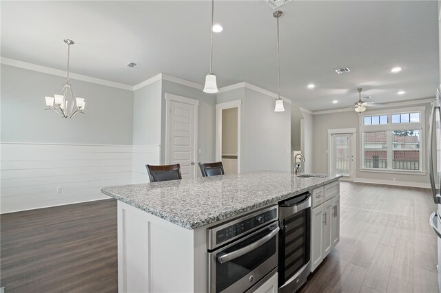 kitchen featuring white cabinetry, beverage cooler, sink, and oven