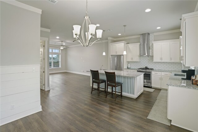 kitchen with stainless steel appliances, dark hardwood / wood-style flooring, white cabinets, wall chimney range hood, and a kitchen island