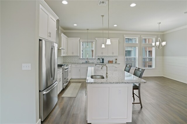 kitchen with stainless steel appliances, white cabinetry, a breakfast bar area, dark hardwood / wood-style floors, and an island with sink