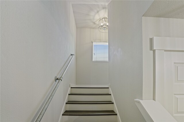 staircase with a notable chandelier